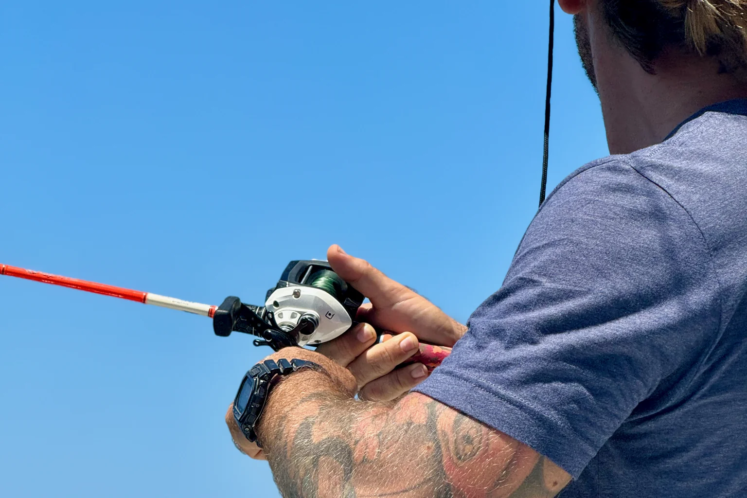 Dettaglio delle mani di un pescatore sulla canna e sul mulinello