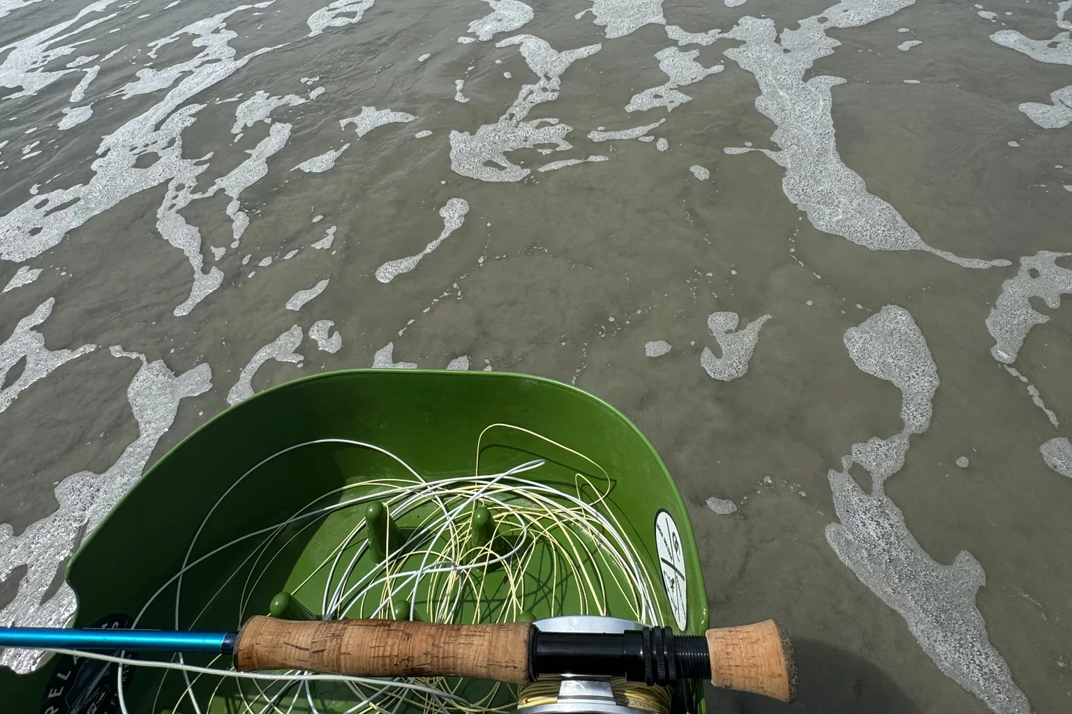 Canna da mosca e cestino per la coda sulla battigia di una spiaggia