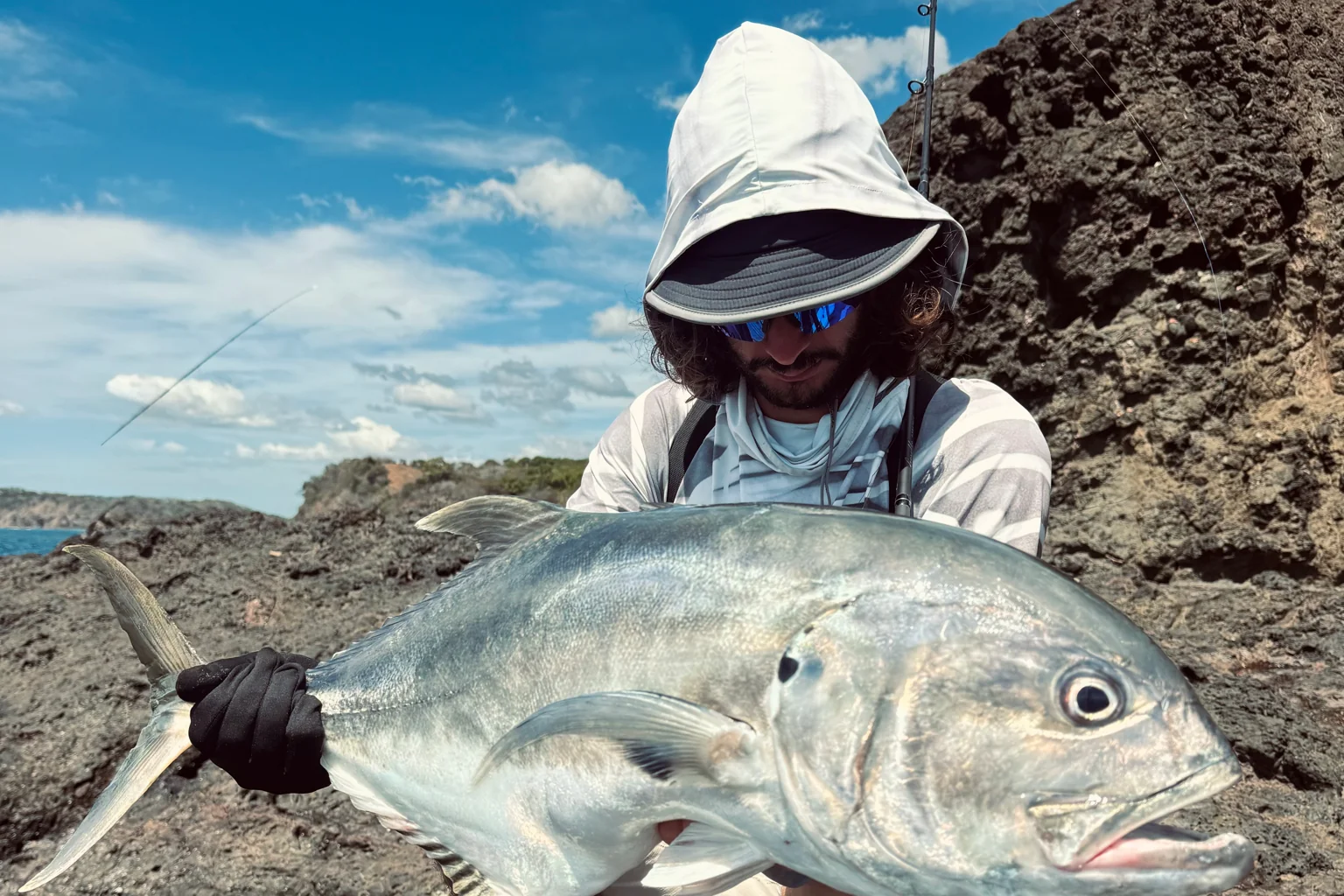 Pescatore con un carangide sulla riva rocciosa